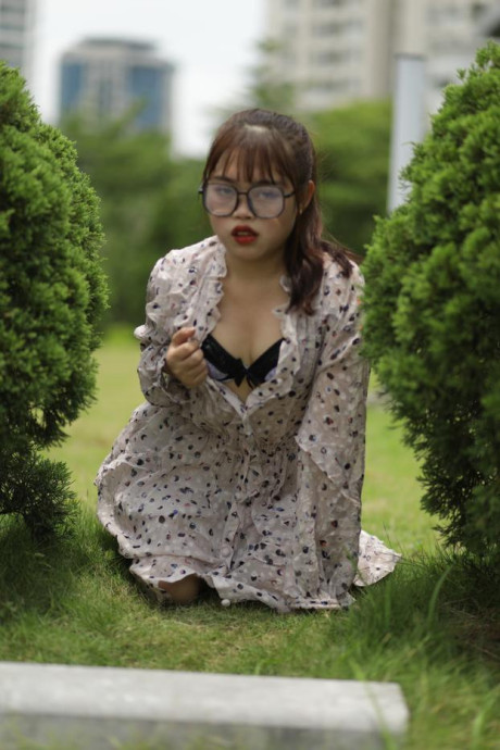 Sweet slut girl broad exposes her brassiere while kneeling between a couple of shrubs - #279512