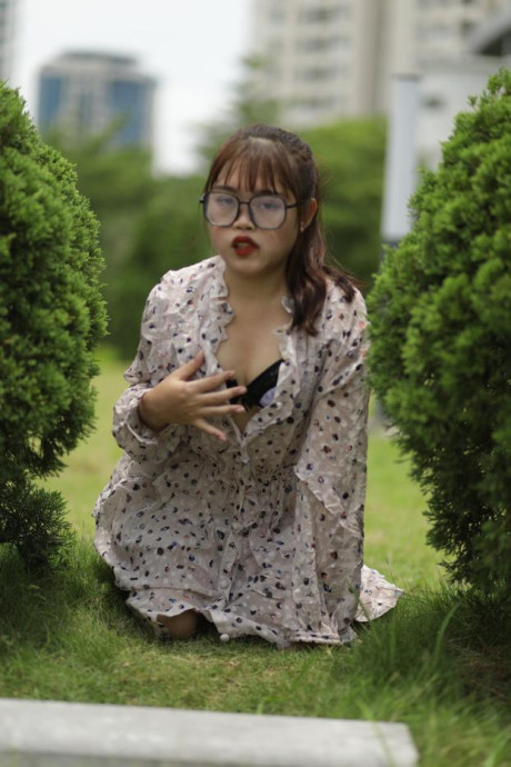Sweet slut girl broad exposes her brassiere while kneeling between a couple of shrubs - #279515