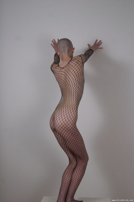 Solo model with a shaved head poses in a fishnet bodystocking - #314761