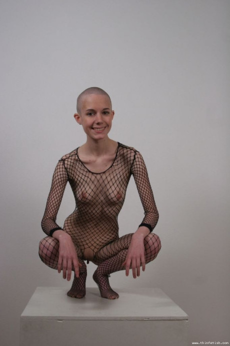 Solo model with a shaved head poses in a fishnet bodystocking #17121