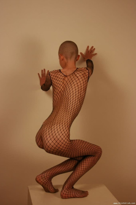 Solo model with a shaved head poses in a fishnet bodystocking - #314769